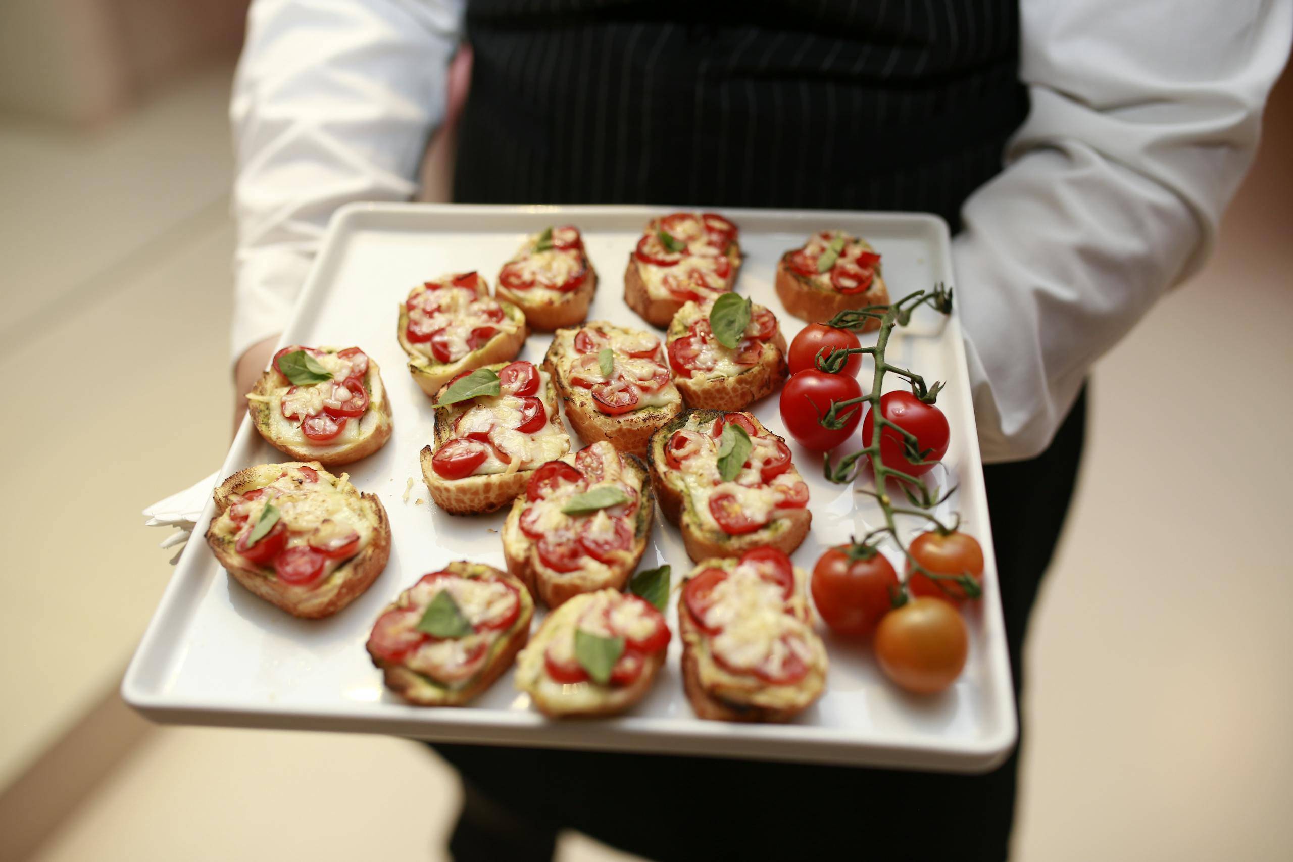 Waiter Holding Tray with Toasted Bread with Tomato and Cheese